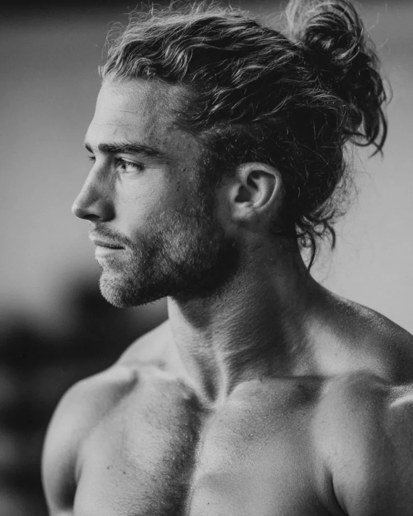 man bun hairstyle on a bodybuilder with long wavy hair and beard, side profile view