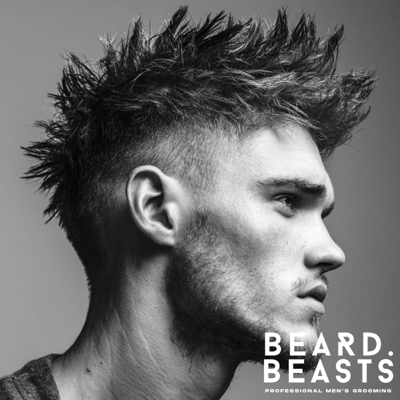 Messy spiky faux hawk hairstyle on a model, featuring voluminous, spiked hair in the center with faded sides. The textured spikes create a bold, edgy look, making this a perfect style for those wanting a rebellious yet defined appearance.