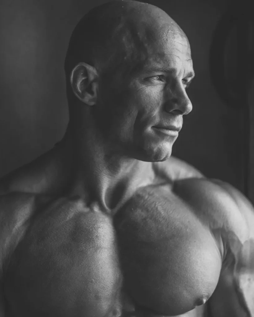 shaved head on a bodybuilder with wide shoulders, side profile view