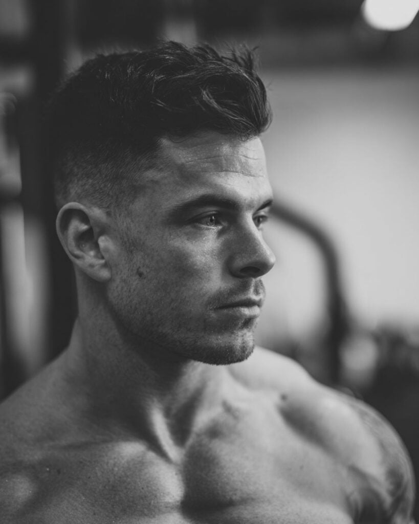 short quiff haircut with fade on a bodybuilder, side profile view in gym setting