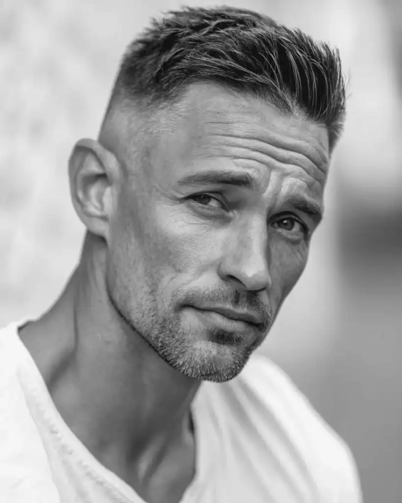 Portrait of a man over 40 with a side-swept crew cut, featuring short sides and a textured top styled diagonally to soften the hairline.