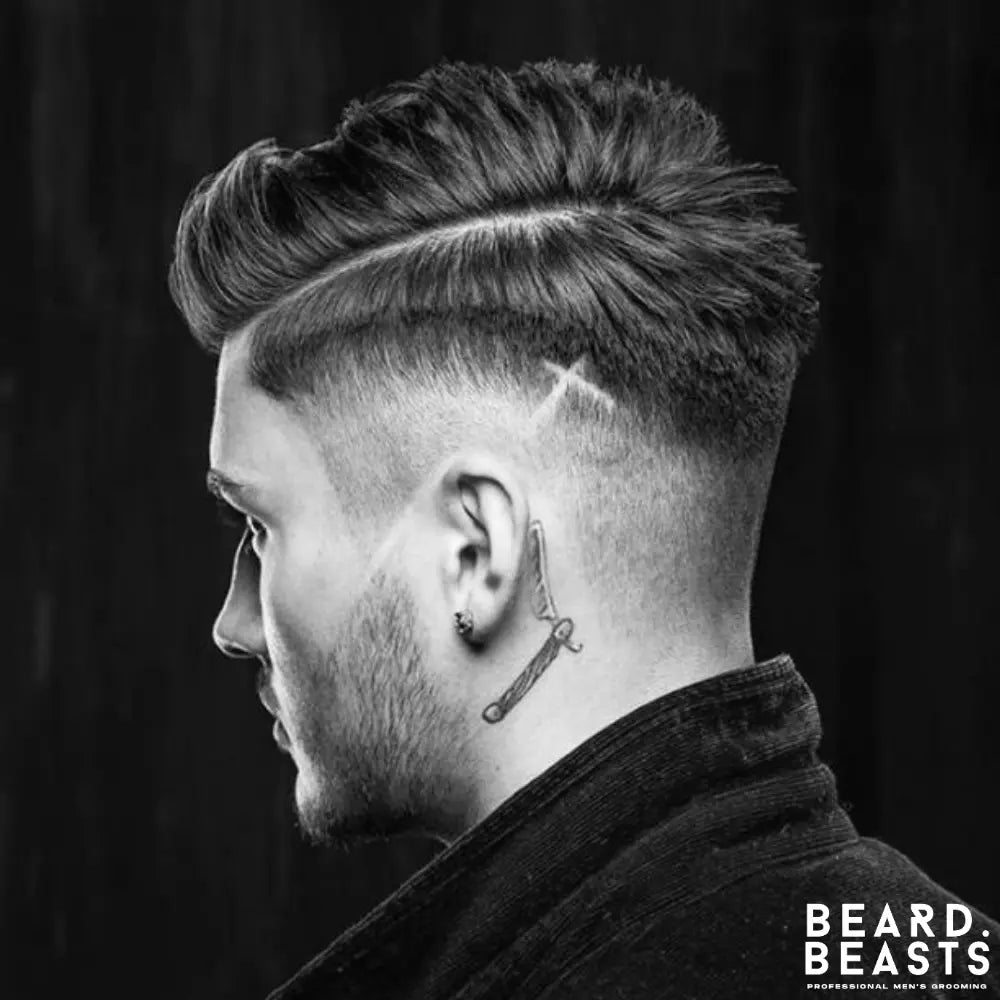 Men’s skin fade haircut with hard part, textured top, and cross pattern hair design on the side.