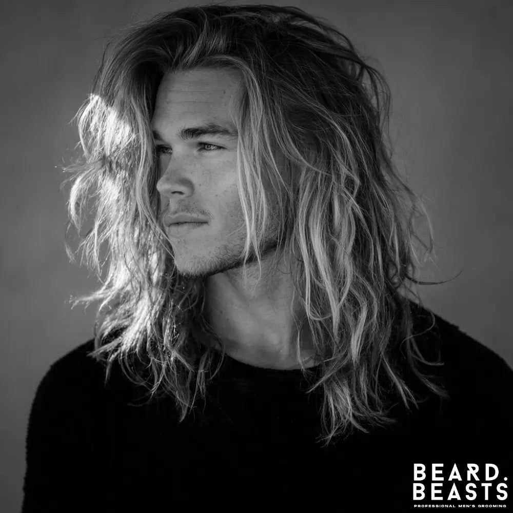 Surfer-inspired long hairstyle for men with sun-kissed highlights, loose waves, and layered texture.