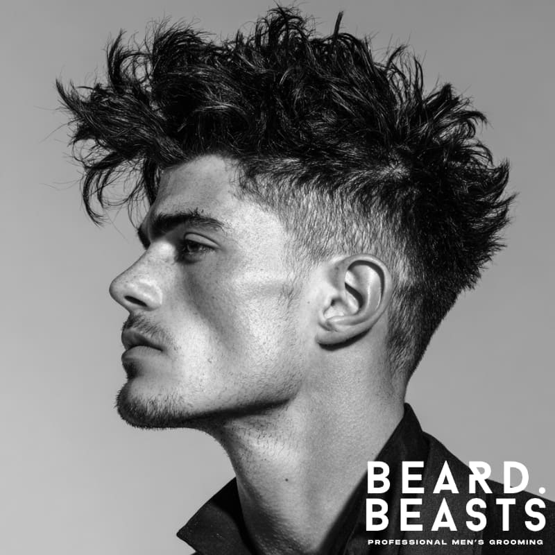 Young male model with a textured faux hawk haircut for men, featuring bold spikes and natural texture for an edgy, modern look.