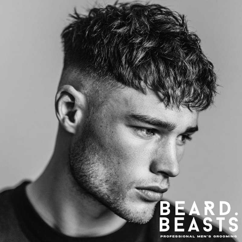 Textured high fade French crop with a voluminous, spiky top and clean fade on the sides, paired with a full beard for a bold, modern look. Ideal for men seeking a low-maintenance, stylish haircut with added texture.