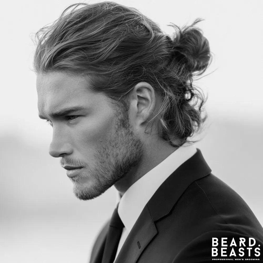 Man with a textured man bun hairstyle featuring loose strands and layered movement for a relaxed yet refined look.