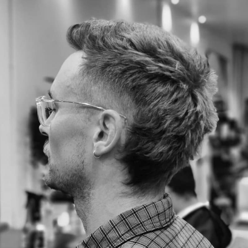 Young male model with a textured mullet fade haircut, combining a bold fade with voluminous texture on top for a modern, statement-making look.