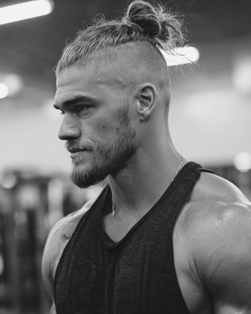 top knot with undercut hairstyle on a bodybuilder in gym setting, side profile view
