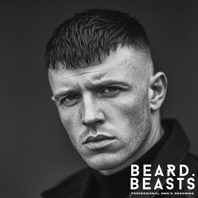 Man with a bald high fade and short textured crop wearing a dark turtleneck and jacket in a monochrome portrait