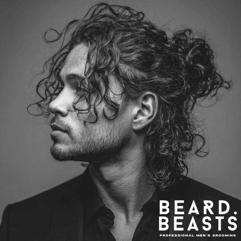 Black and white side profile of a man with a half-up, half-down long curly hairstyle, featuring textured volume and a tied crown section.