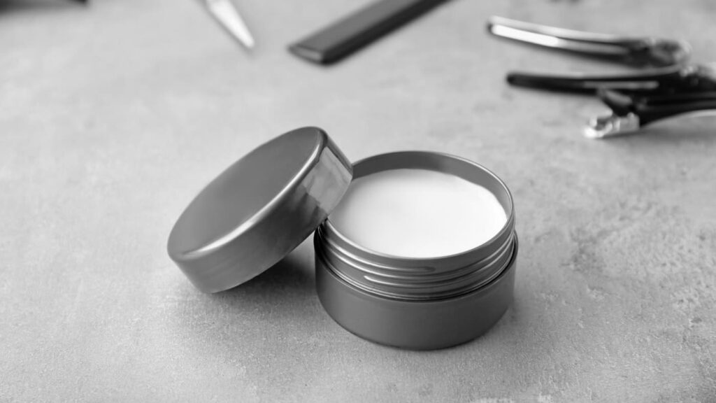 Open jar of hair clay styling product on a barber’s workstation