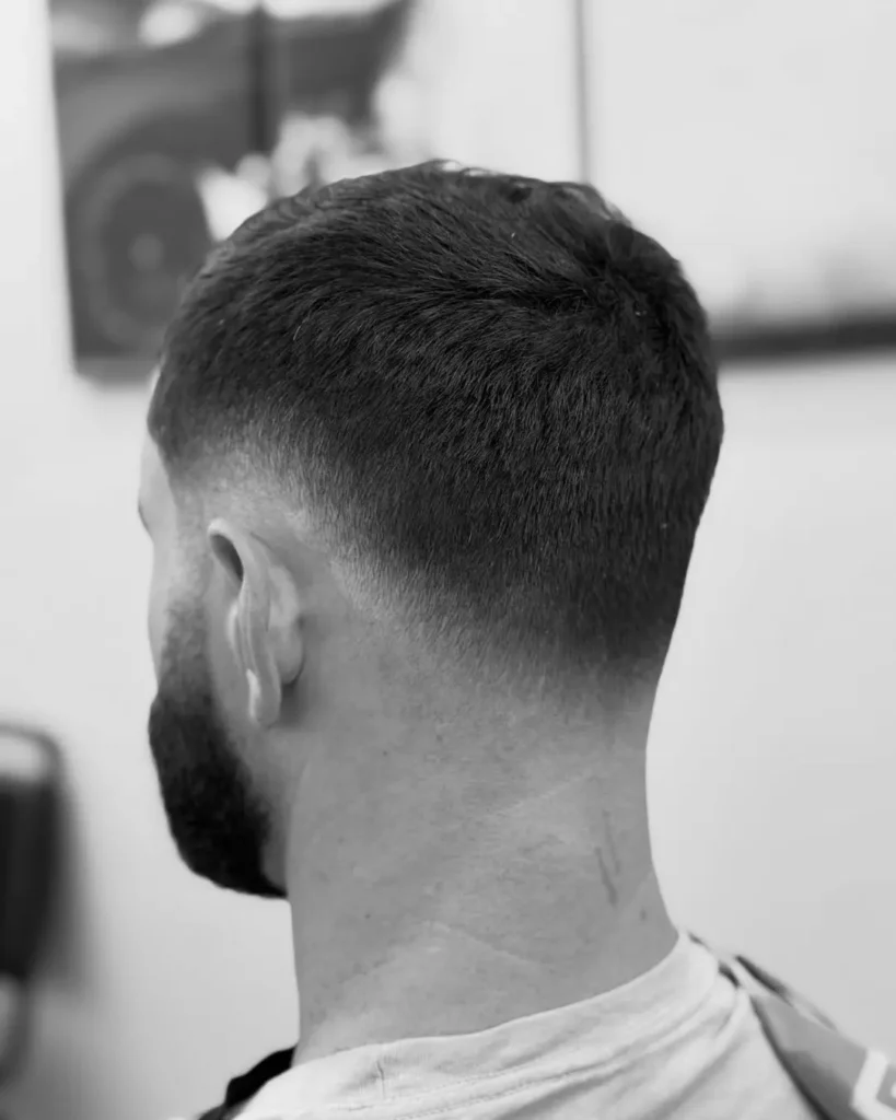 drop fade haircut curving down behind the ear with full beard, rear view