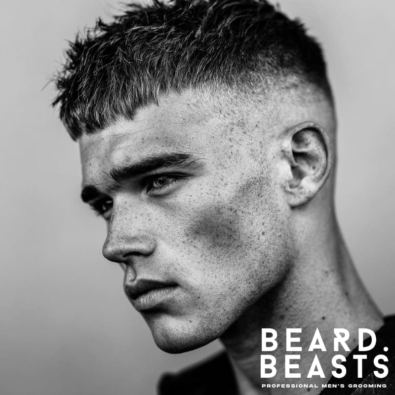 High fade blunt fringe haircut for men, featuring a defined, straight-across fringe paired with a clean, sharp fade on the sides.