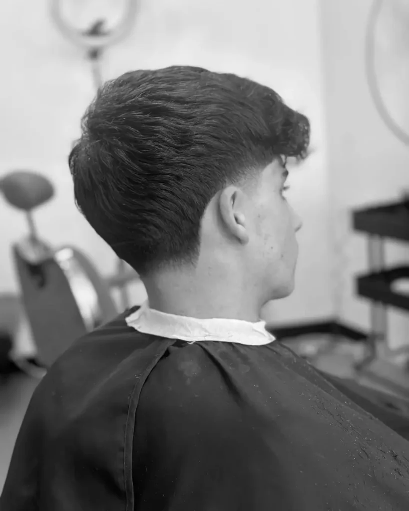 Man with a mid taper and longer textured hair, showing how a mid taper keeps the sides softer while tidying the neckline and sideburns.