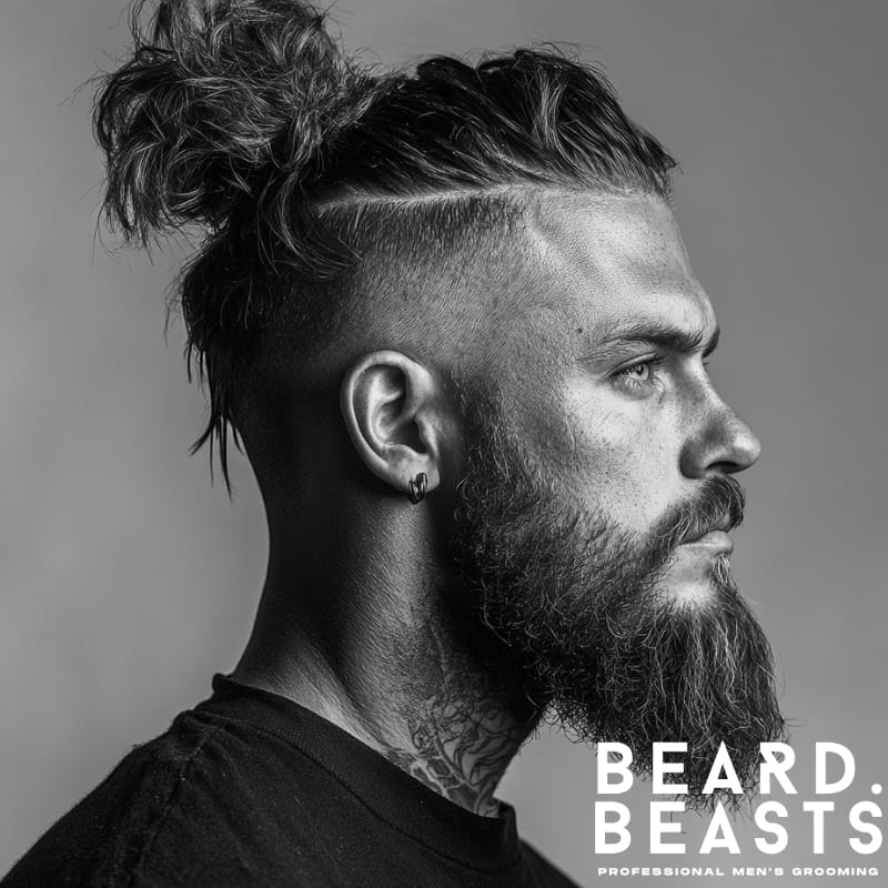 Side profile of a man with a Viking-inspired hairstyle featuring a high faded undercut and a textured wavy man bun. He has a full beard, earrings, and visible neck tattoos, enhancing the rugged, masculine style. This look is a bold example of mens long wavy hairstyles, combining natural wave with structured grooming. The black and white image includes the Beard Beasts logo, emphasizing professional men’s grooming.