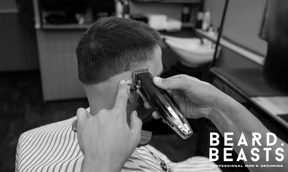 A barber using clippers to sharpen a man's short faded haircut, demonstrating regular maintenance.