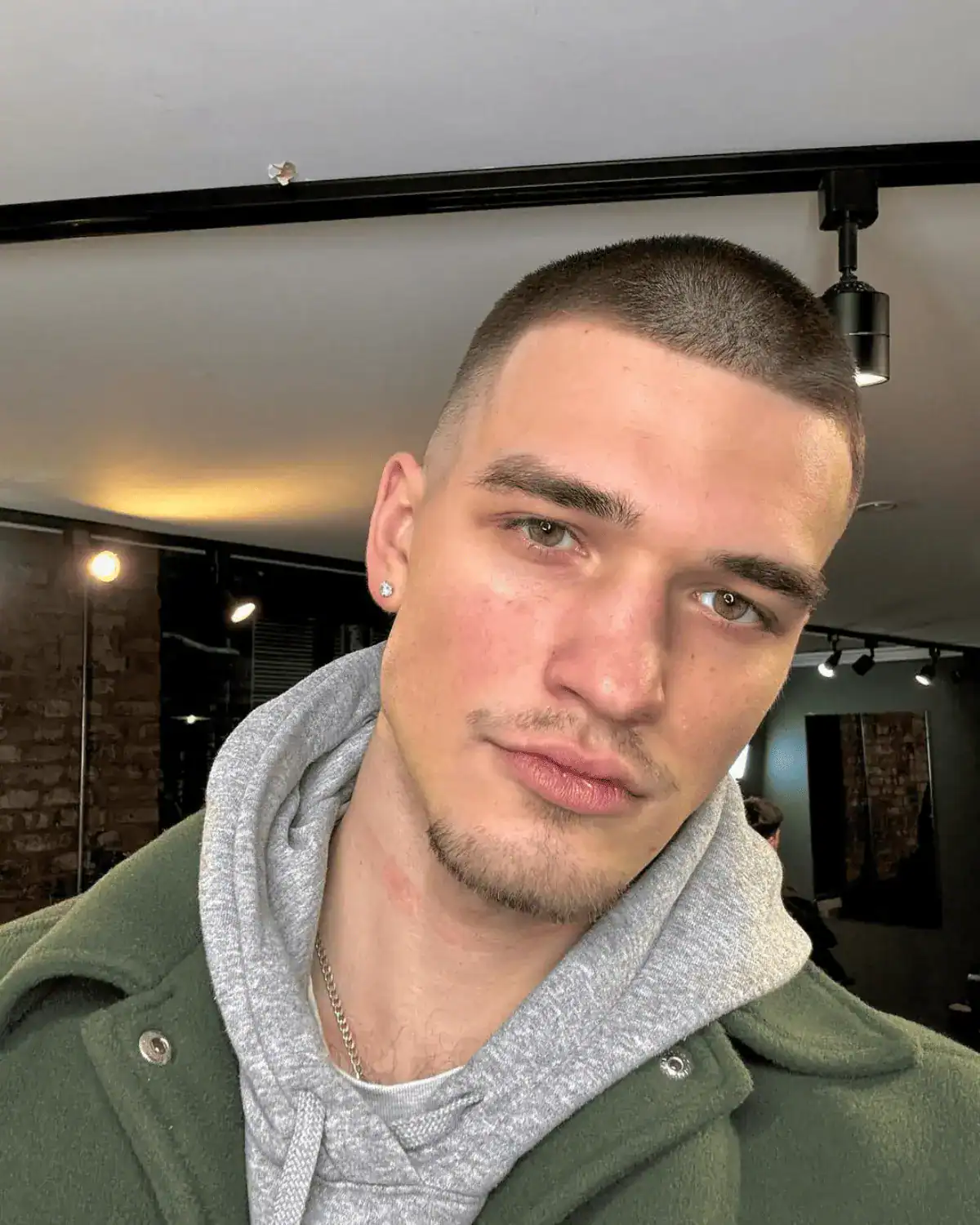 Buzz cut with a light goatee and circle beard on a man, showing minimal cheek growth and focused facial hair around the chin and moustache