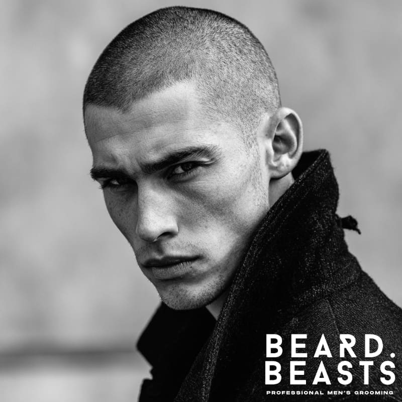 Man with a classic burr cut hairstyle, featuring a clean, uniform look with short hair all over. Styled with a sharp, masculine edge, and dressed in a black jacket, exuding confidence and sophistication.