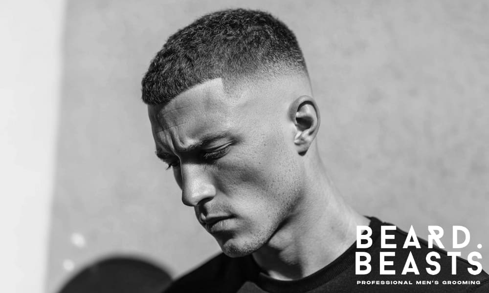 Black and white image of a man with strong facial features, highlighting how his short haircut enhances his jawline.