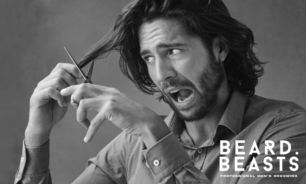 Man with long, thick hair trimming his hair with scissors, showcasing a DIY grooming moment—ideal for men maintaining their long haircuts at home.