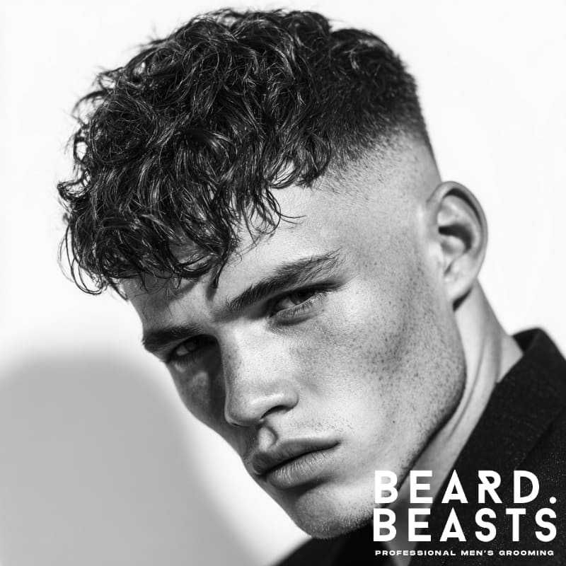 Men's short wavy textured fringe with a fade, creating a dynamic and voluminous look.