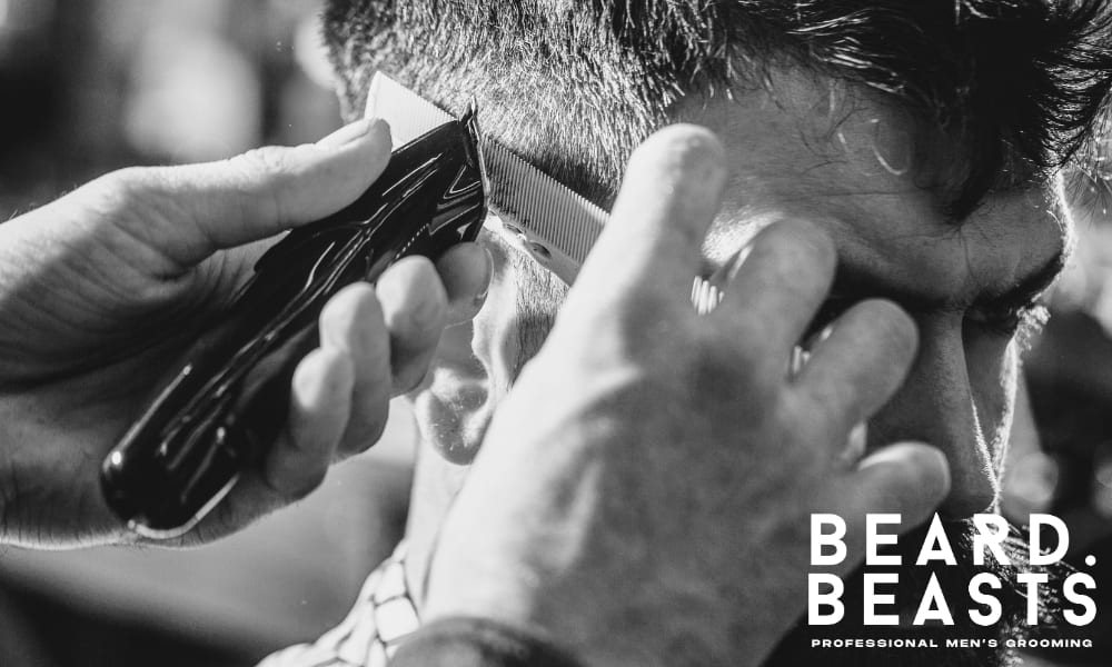 Barber trimming a client's hair with clippers during a professional haircut session. Close-up shot highlighting the precision and care involved in maintaining a sharp hairstyle.