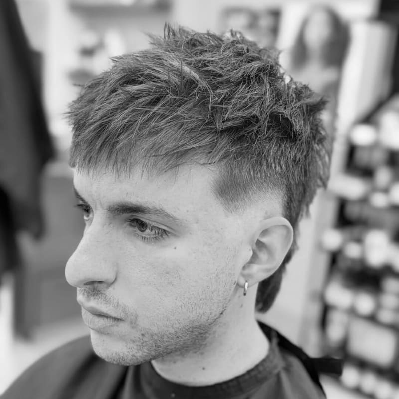 Close-up of a burst fade haircut with textured, spiked layers on top and a clean fade around the sides. A bold, dynamic look with natural movement and volume.