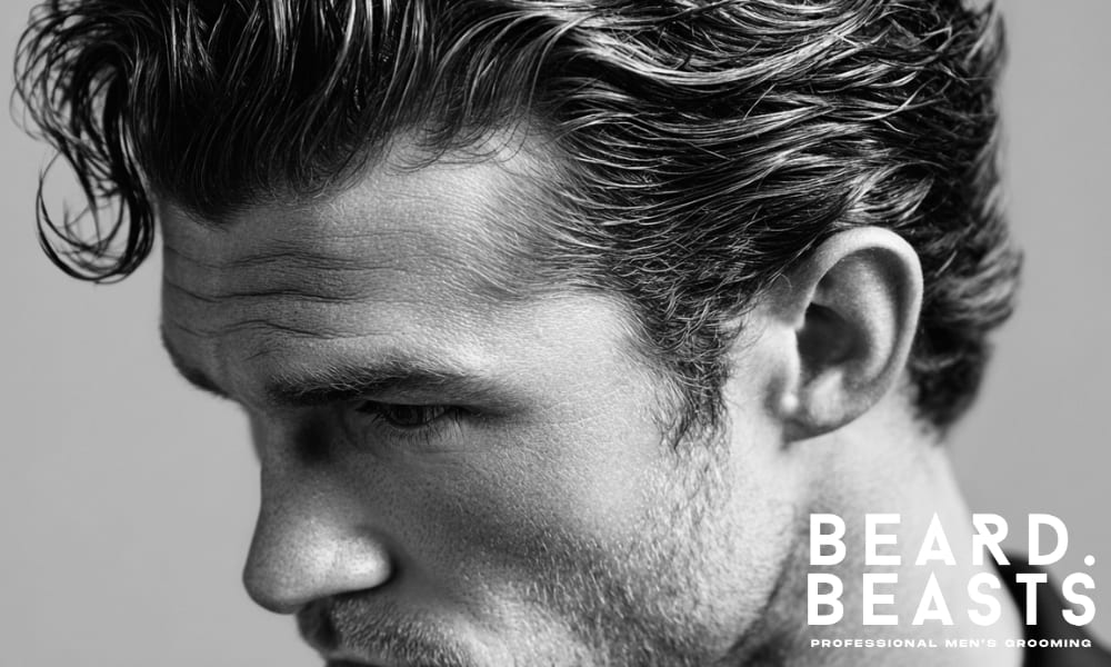 Close-up of a man with styled hair, featuring defined waves and a polished, sophisticated look.