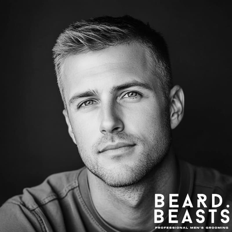 A man with a classic crew cut, clean tapered sides, and a natural textured top, wearing a casual olive shirt.