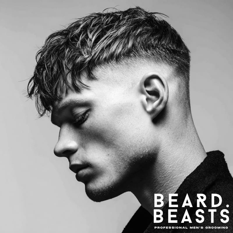 Drop fade textured fringe haircut with soft, voluminous texture on top and a gradual fade on the sides. A stylish, modern look that offers a seamless blend of contrast and texture.