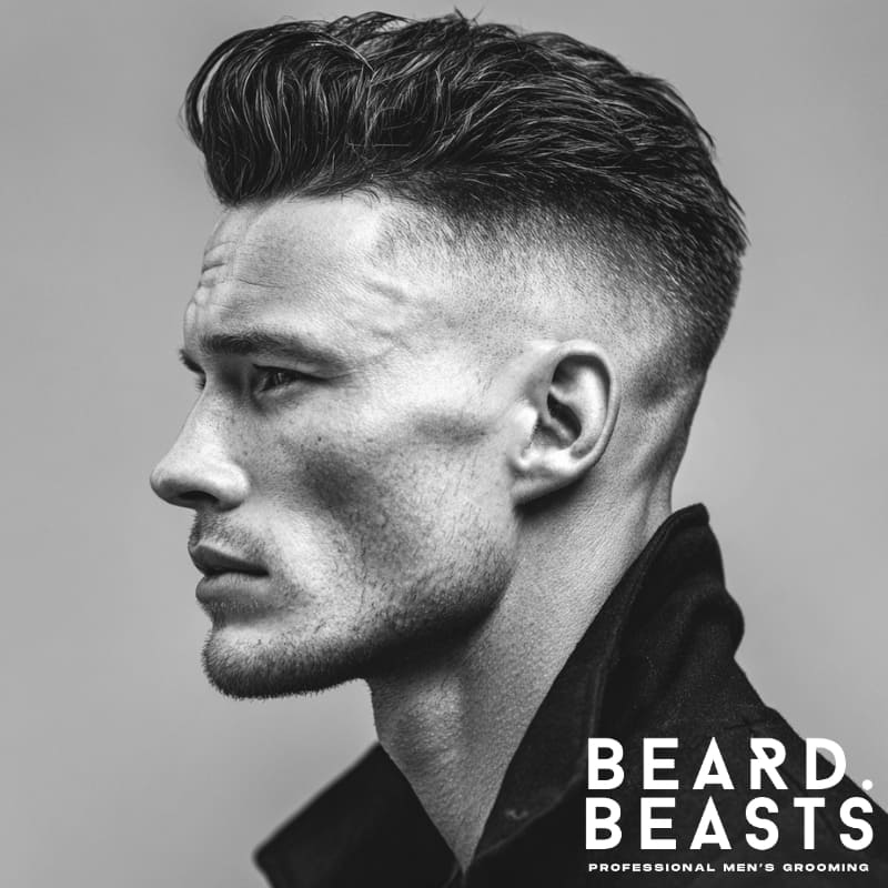 High fade textured slick back hairstyle for men with sharp contrast between the voluminous top and faded sides.