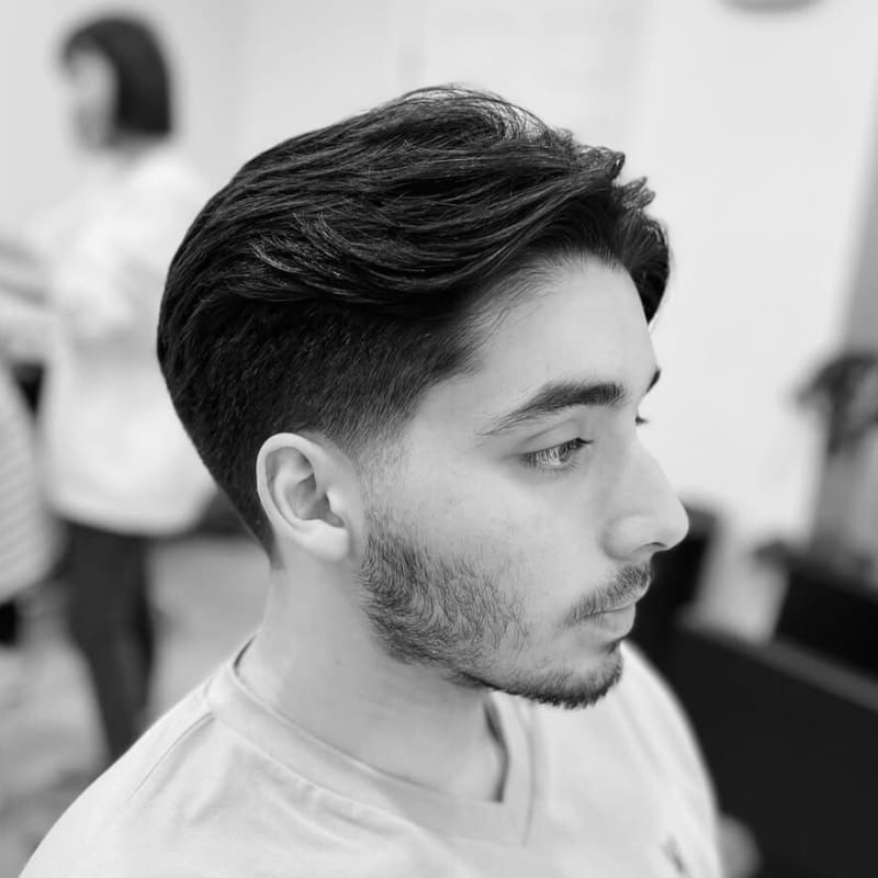 Man with a layered taper cut featuring soft texture on top and neatly tapered sides, styled to enhance natural shape and balanced proportions.