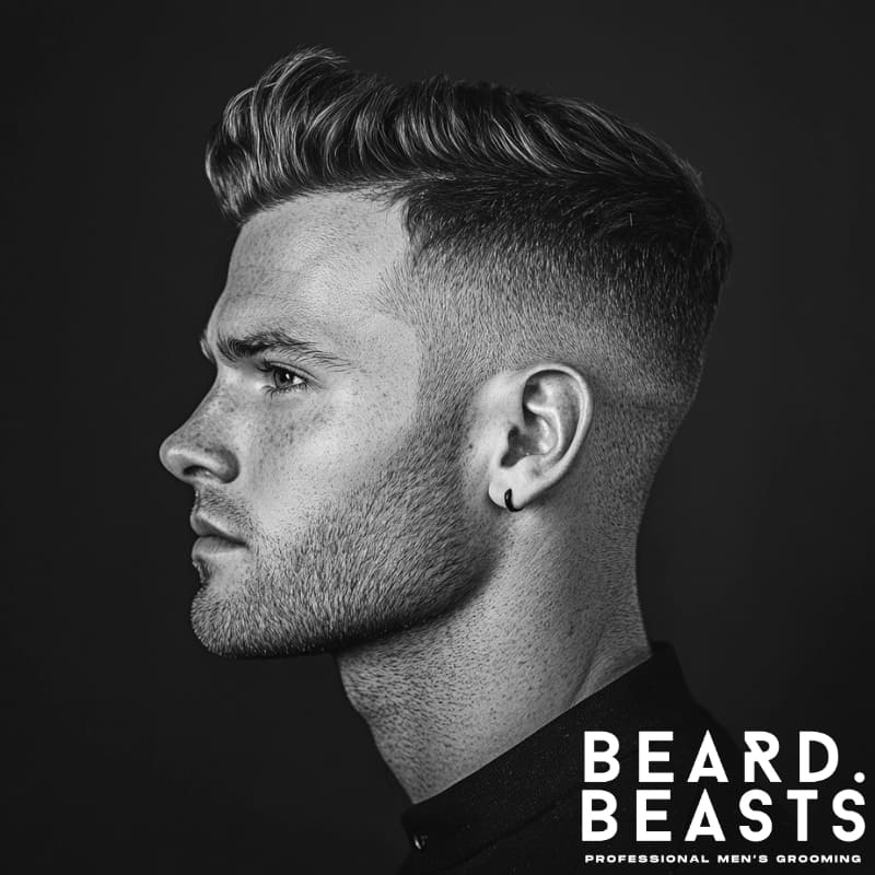 Black and white side profile of a man with a short quiff haircut, featuring a clean fade and styled top.