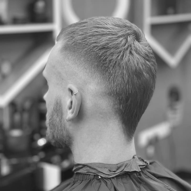 Short mohawk fade on a man with straight hair—tapered sides and defined shape ideal for bold hairstyles for guys with short straight hair.