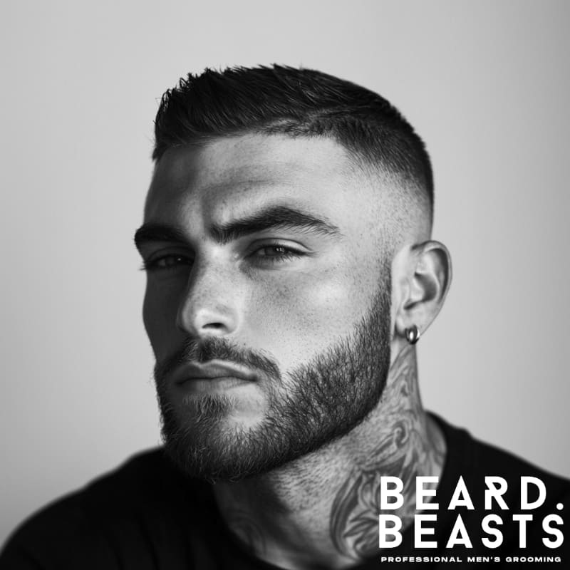 Black and white portrait of a man with a skin fade and short top haircut, a bold and breathable choice for men’s summer haircuts.