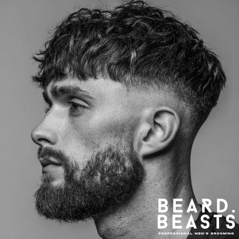 Skin fade textured fringe haircut with curly, voluminous texture on top and a clean fade on the sides. A modern, high-contrast style that enhances texture and volume.