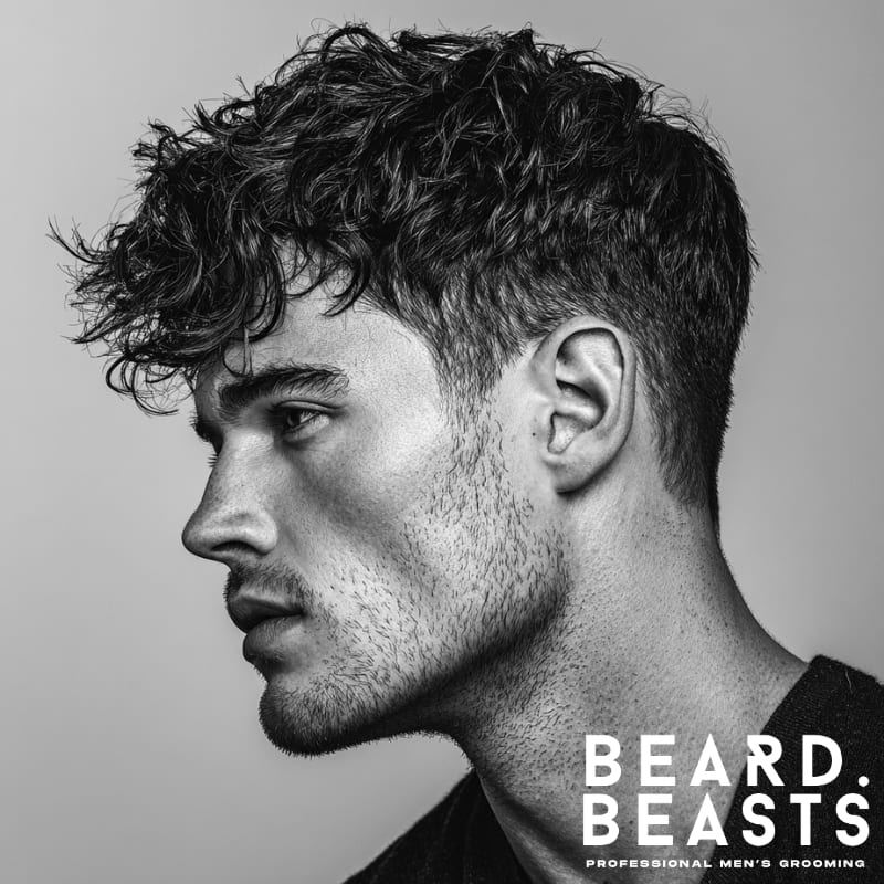 Wavy textured fringe haircut with natural, voluminous waves and a clean fade on the sides. A modern, stylish look that enhances texture and adds movement.