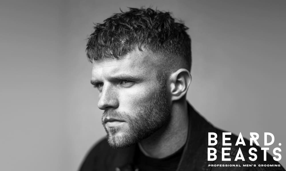 Black and white portrait of a man with a textured crop hairstyle, styled with matte finish—ideal example of a haircut that suits hair paste.