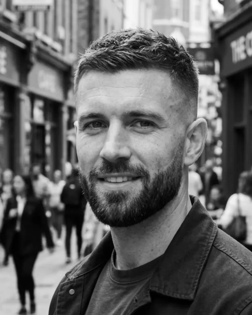 Crew cut fade with a short beard, showing a short textured top with faded sides and shaped facial hair.
