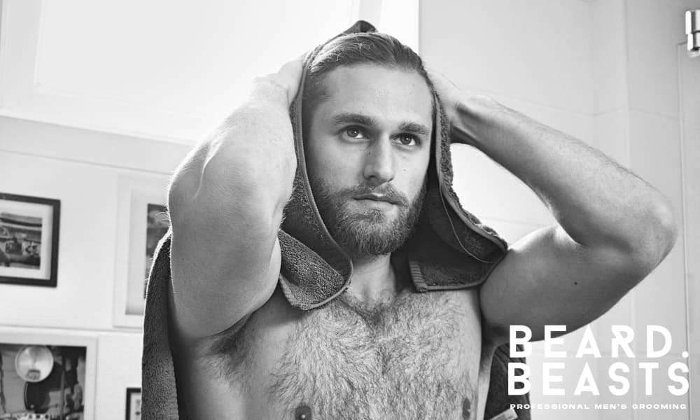 Man drying his hair with a towel as part of a morning routine for men with oily hair.