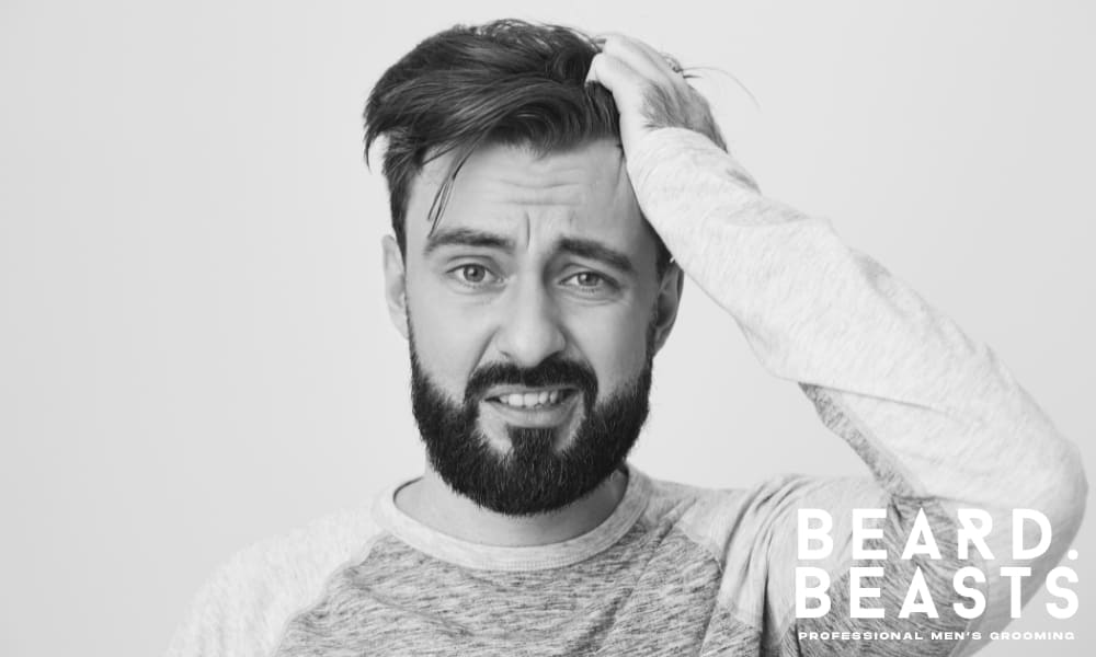 Frustrated man running hand through flat hair—highlighting common grooming mistakes that cause flat hair in men.