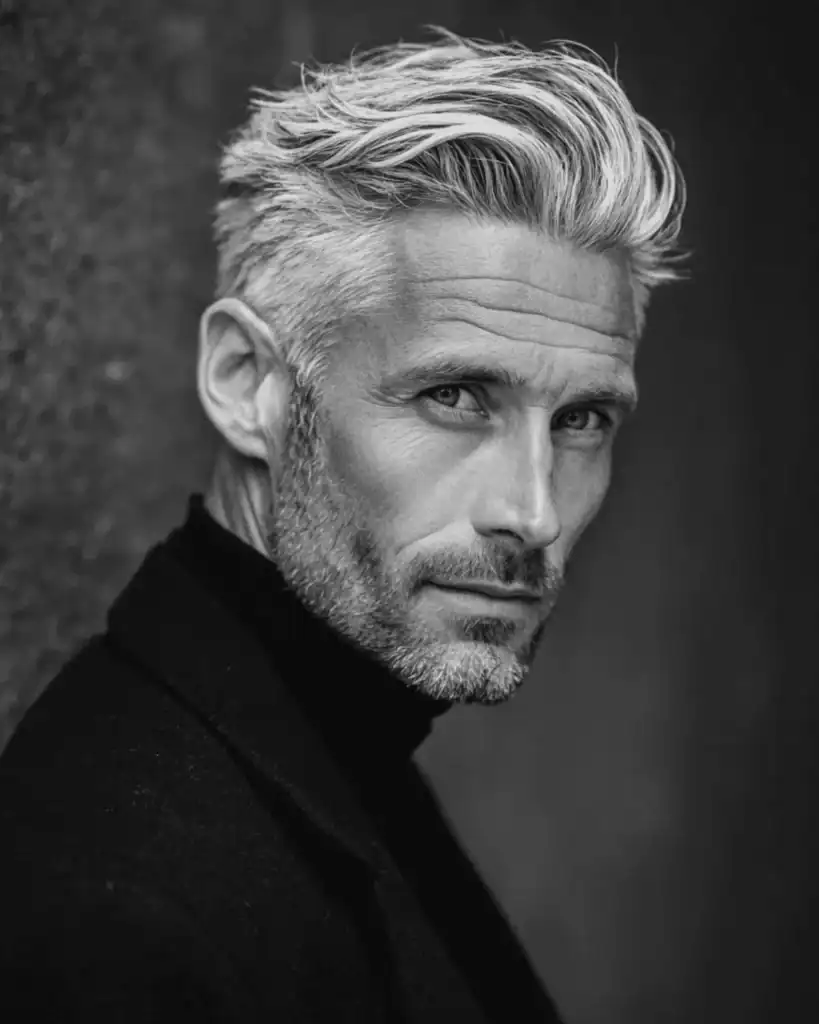 A portrait of a handsome older man sporting a heavy stubble beard, featuring salt-and-pepper facial hair that adds rugged definition to the jawline.