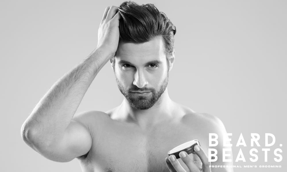 Shirtless man applying a grooming product with one hand while refining his hairstyle, emphasizing the importance of finishing touches in styling.