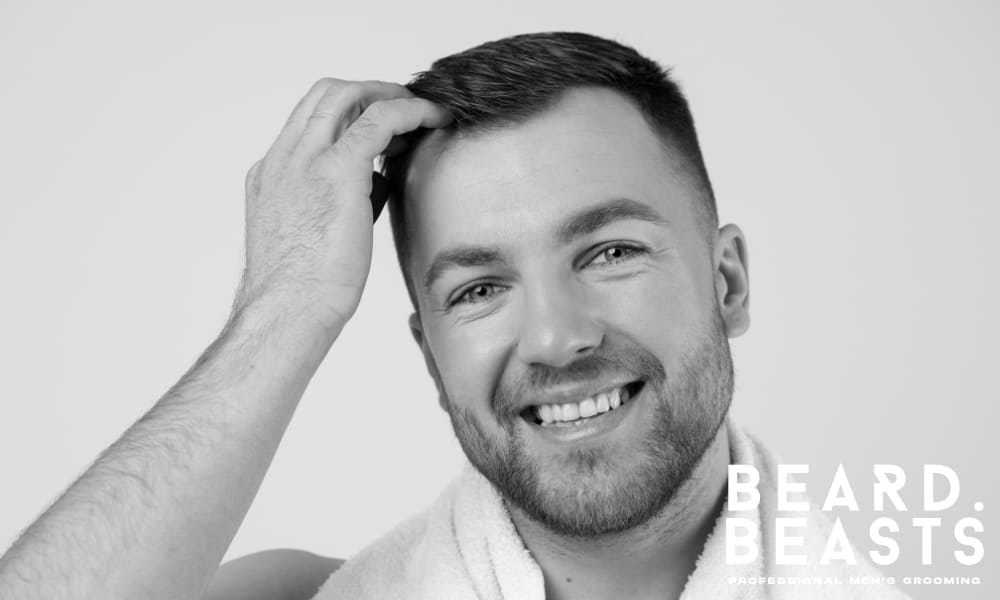 Smiling man grooming his hair with a fresh, clean look, wearing a white towel—representing healthy grooming habits with hair paste.