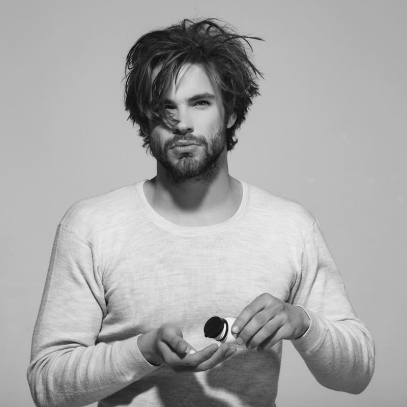 Man with messy hair preparing to apply matte clay for textured styling