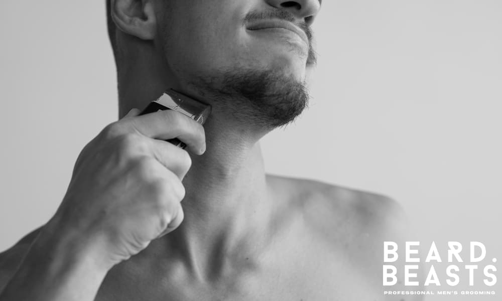Close-up of a man using an electric trimmer to shape his beard neckline, focusing on clean grooming and precise edge maintenance.