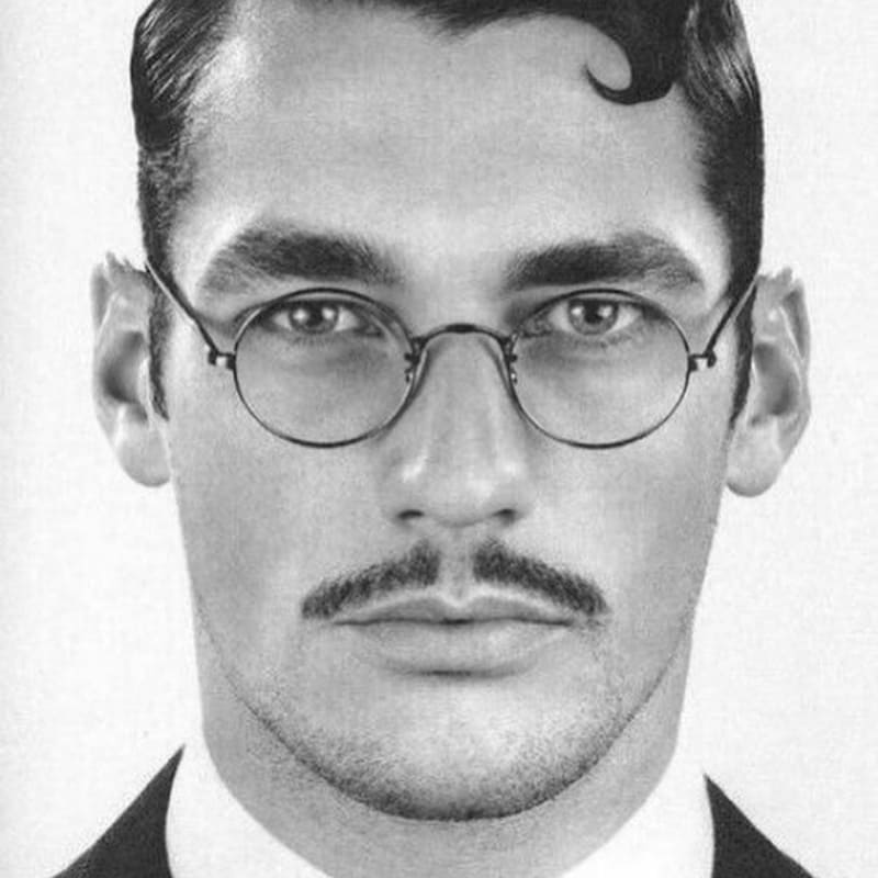 Man with a classic pencil mustache wearing round glasses—features a neatly trimmed, straight mustache above the upper lip with clean edges and vintage styling.