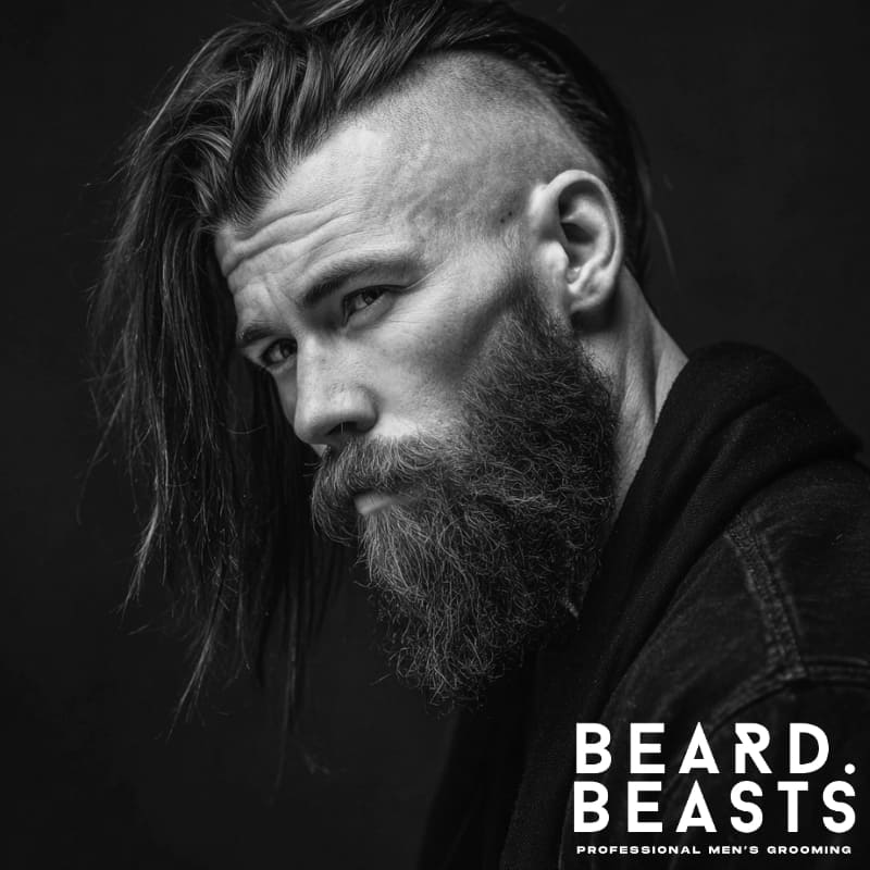 Man with a disconnected undercut and long beard, showcasing sharp contrast between shaved sides and full facial hair