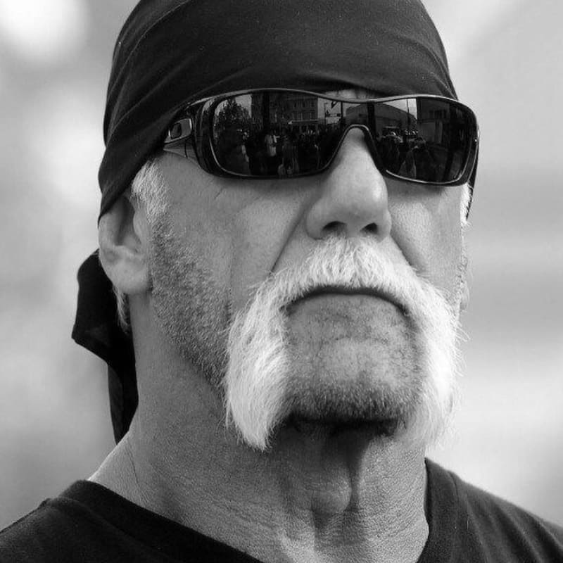 Black and white photo of a man with a white horseshoe mustache, sunglasses, and bandana — iconic example of the classic biker mustache style