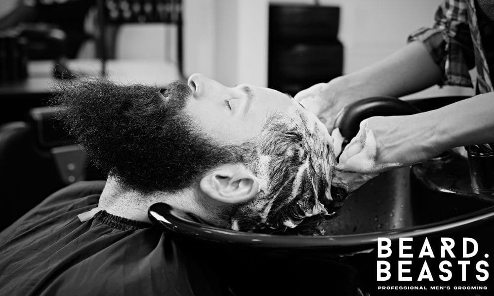 Man with long hair getting a professional shampoo at a salon sink—demonstrating proper long hair washing technique and care.